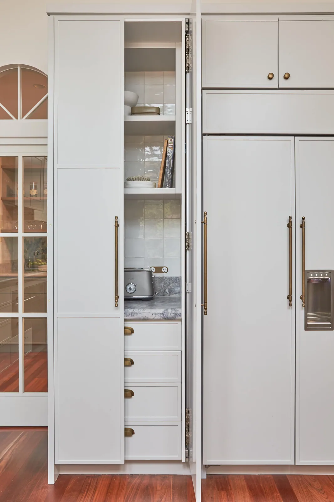 Custom kitchen pantry with tall shaker-style cabinetry, brass hardware, and integrated shelving—highlighting functional elegance with subtle moulding accents.