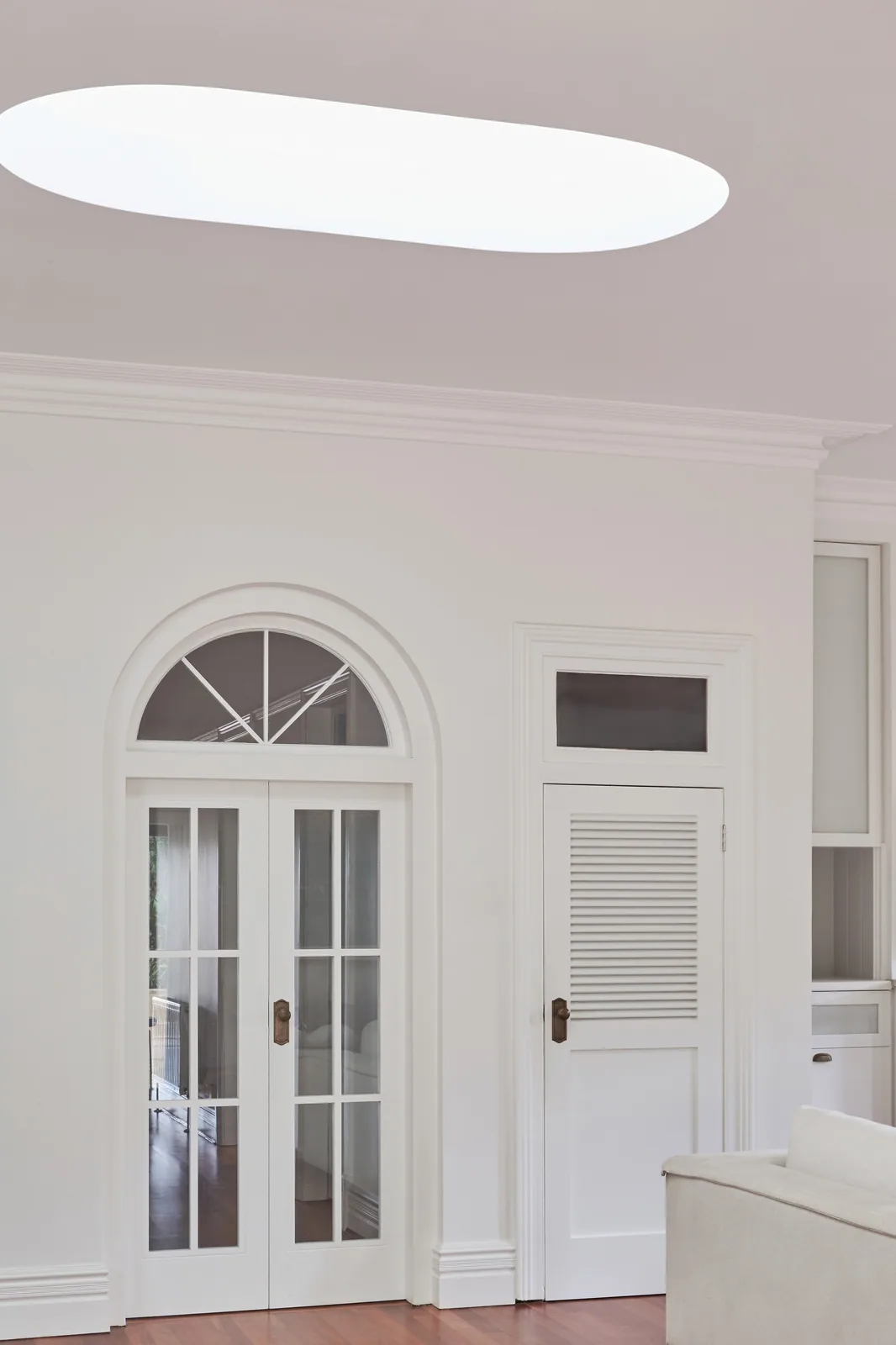 Bright transitional space featuring arched double glass doors, skylight-enhanced natural lighting, and refined Intrim mouldings framing ceiling and doorways—ideal for heritage-inspired interiors.