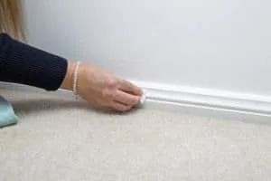 A woman's hand using a magic eraser to wipe clean skirting boards