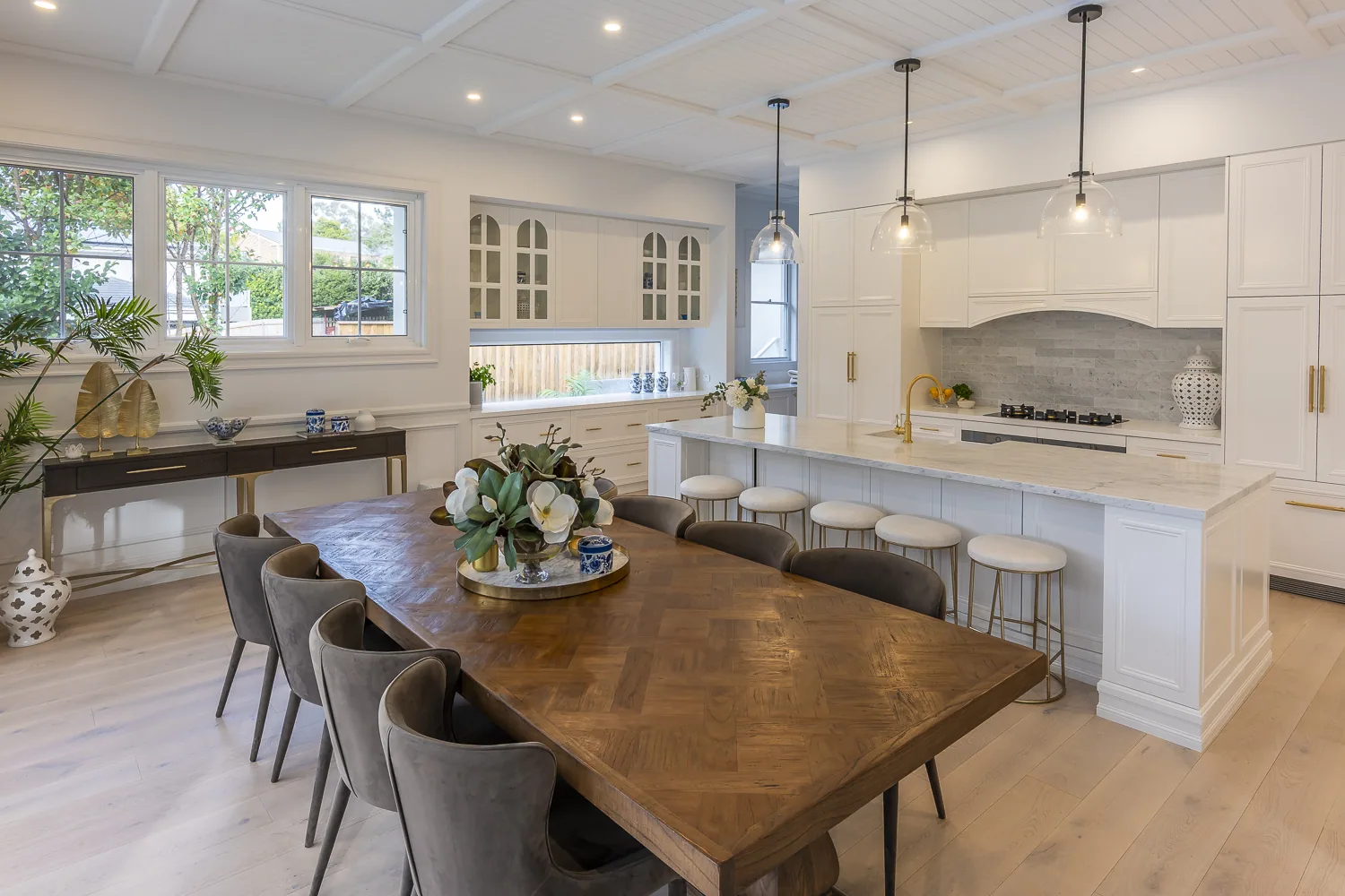 Open-plan kitchen and dining area featuring decorative timber mouldings, coffered ceiling panels, detailed cornice, and panelled island joinery