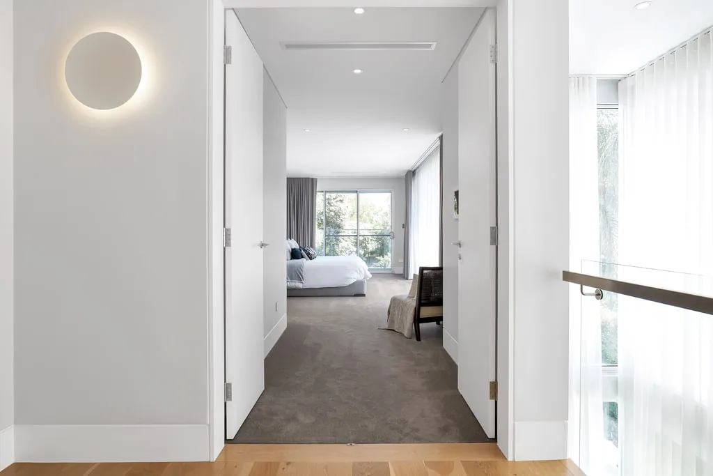 Minimalist hallway with square-edge timber skirting boards and clean-lined architraves leading into a contemporary bedroom.